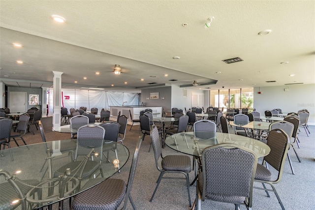 carpeted dining area featuring decorative columns and a textured ceiling