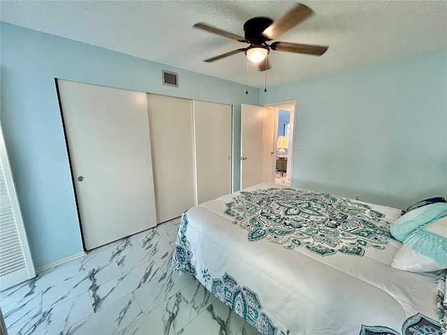 bedroom featuring ceiling fan, a textured ceiling, and a closet