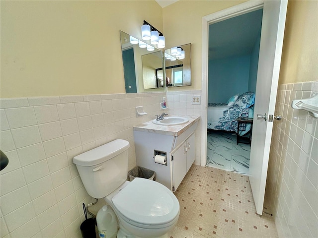 bathroom with vanity, tile walls, and toilet