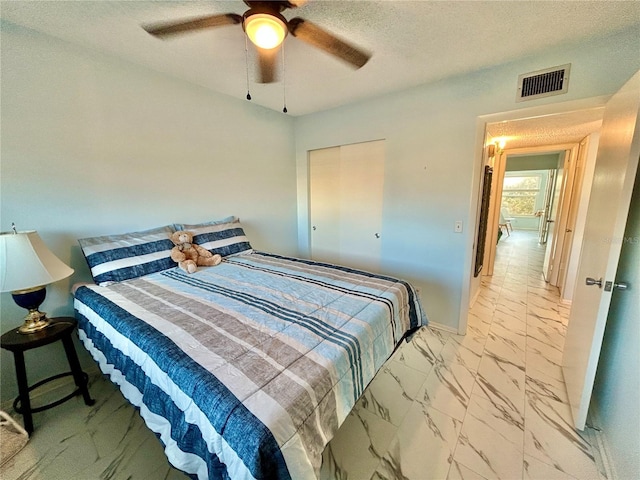 bedroom with ceiling fan and a textured ceiling