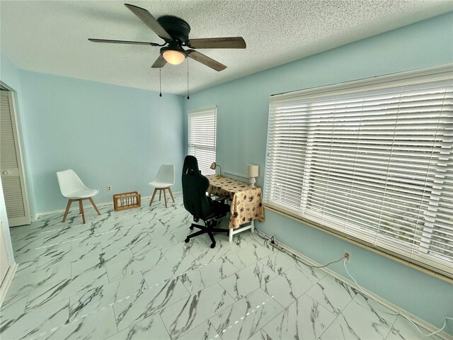 unfurnished office with ceiling fan and a textured ceiling