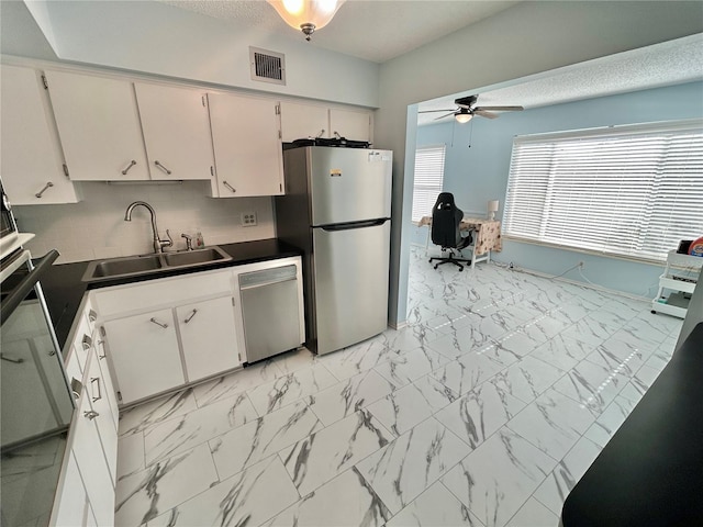 kitchen with sink, tasteful backsplash, appliances with stainless steel finishes, ceiling fan, and white cabinets