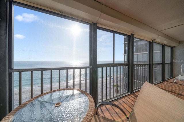 sunroom / solarium with a water view, a wealth of natural light, and a view of the beach