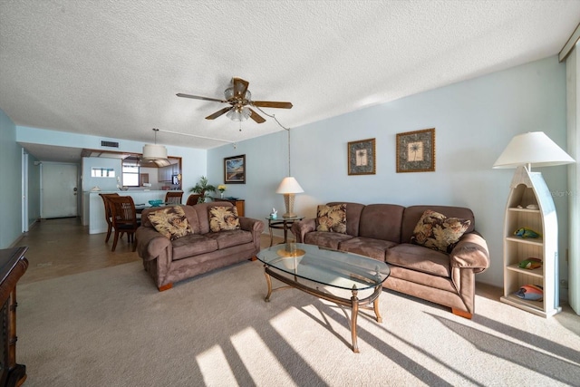 carpeted living room with ceiling fan and a textured ceiling