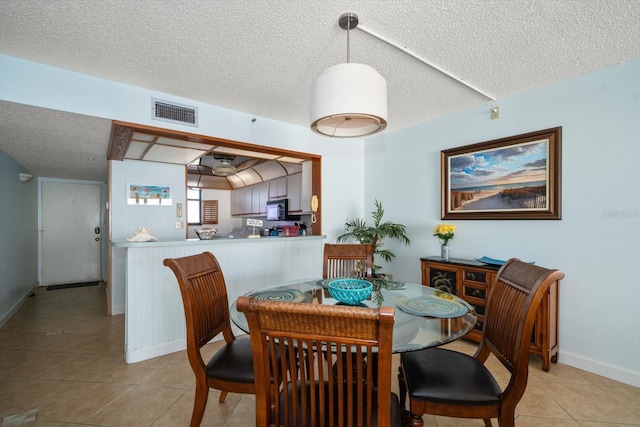 dining area featuring light tile patterned flooring and a textured ceiling