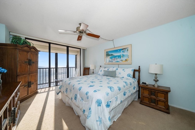 carpeted bedroom featuring expansive windows, a water view, ceiling fan, and access to outside