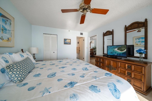 carpeted bedroom with ceiling fan, a closet, and a textured ceiling