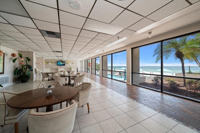 dining room featuring light tile patterned floors and a drop ceiling