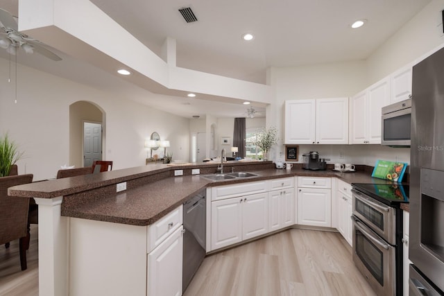 kitchen featuring sink, appliances with stainless steel finishes, kitchen peninsula, light hardwood / wood-style floors, and white cabinets