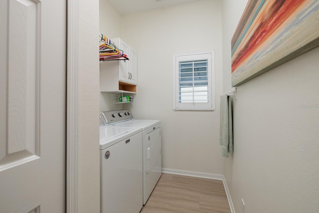 washroom featuring washer and dryer, light hardwood / wood-style flooring, and cabinets