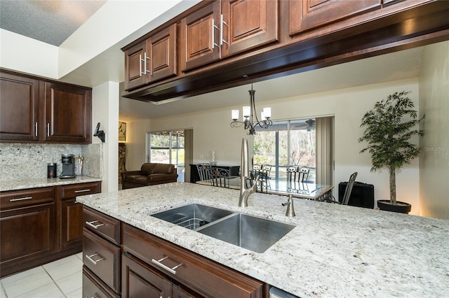 kitchen with light tile patterned flooring, sink, light stone counters, and decorative backsplash