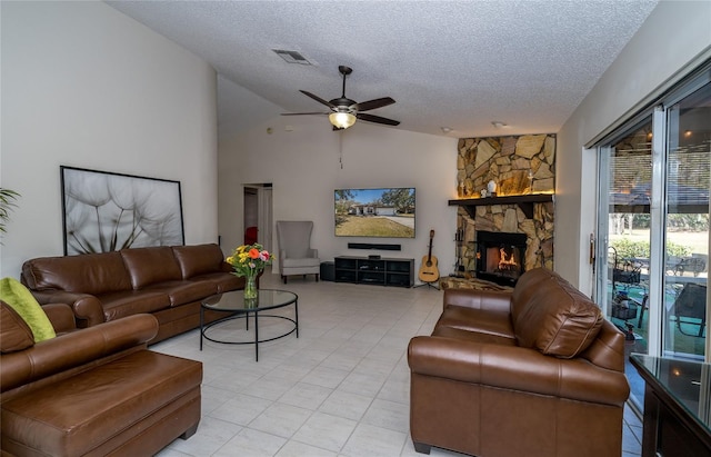 tiled living room featuring ceiling fan, a stone fireplace, lofted ceiling, and a textured ceiling