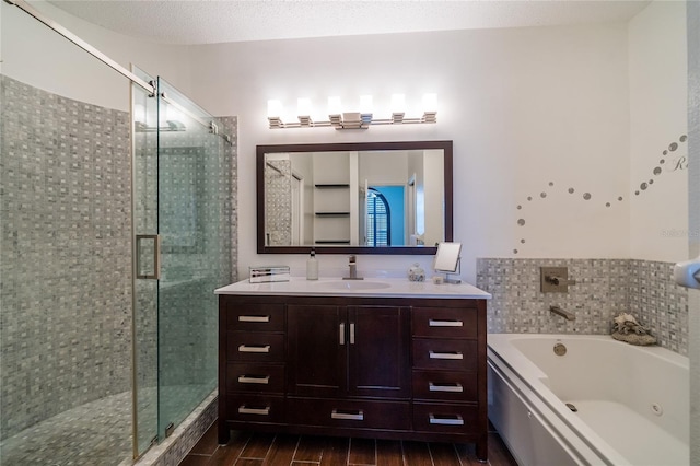 bathroom featuring independent shower and bath, vanity, and a textured ceiling