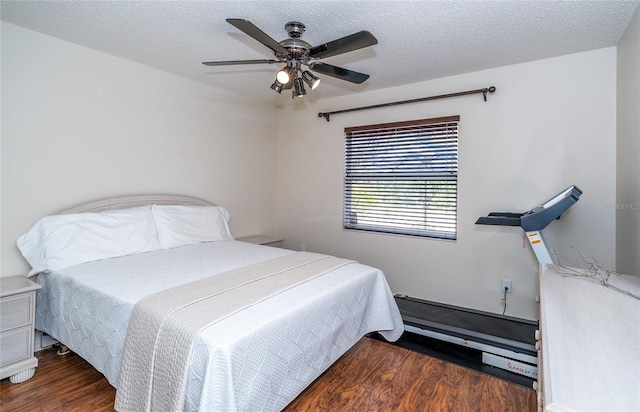 bedroom with ceiling fan, dark hardwood / wood-style floors, and a textured ceiling