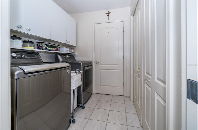 clothes washing area featuring washer and clothes dryer, cabinets, and light tile patterned flooring