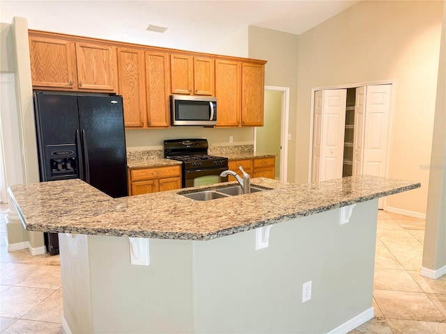 kitchen with an island with sink, sink, a breakfast bar area, and black gas range