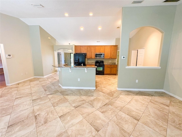 kitchen with high vaulted ceiling, a center island with sink, a kitchen breakfast bar, light stone countertops, and black appliances