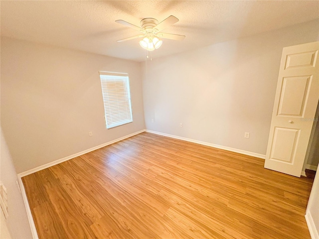 empty room with a textured ceiling, ceiling fan, and light hardwood / wood-style flooring