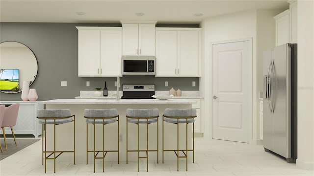 kitchen featuring appliances with stainless steel finishes, a breakfast bar area, a center island with sink, and white cabinets