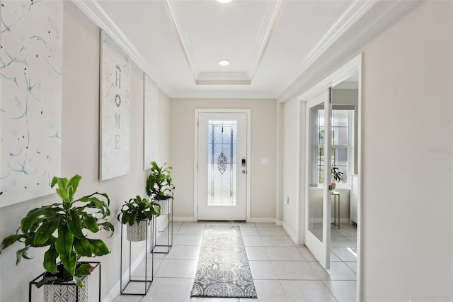 tiled entrance foyer with ornamental molding and a tray ceiling