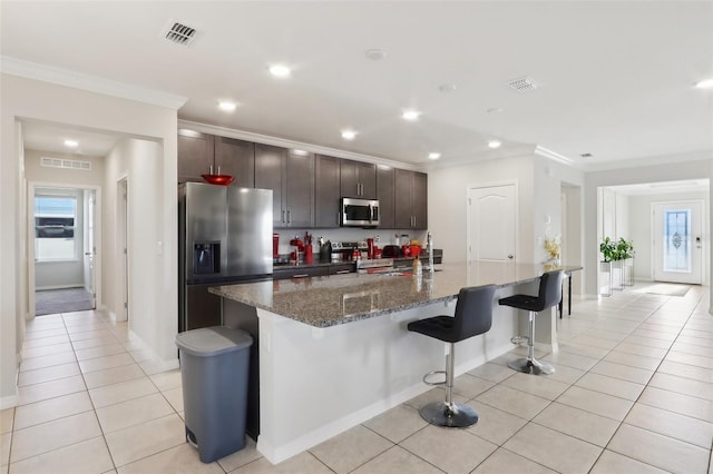 kitchen with dark brown cabinets, appliances with stainless steel finishes, a breakfast bar, and a center island with sink