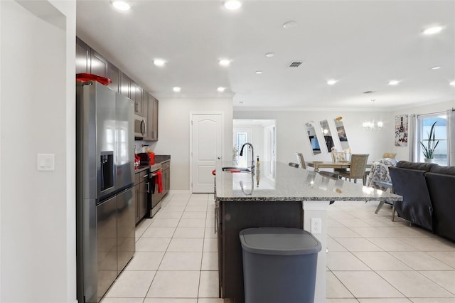 kitchen featuring light tile patterned floors, sink, stainless steel appliances, ornamental molding, and an island with sink