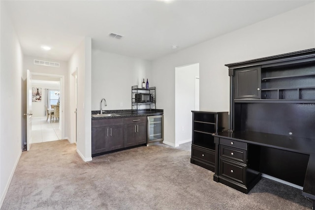 interior space featuring dark brown cabinetry, sink, light colored carpet, and beverage cooler