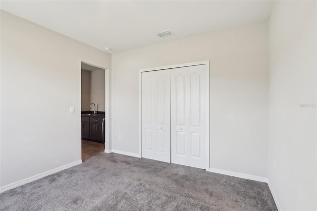 unfurnished bedroom featuring light colored carpet, sink, and a closet