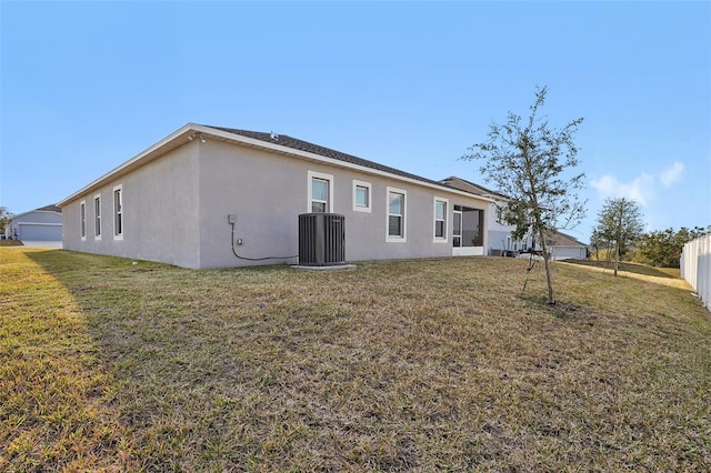 back of house with central AC and a lawn