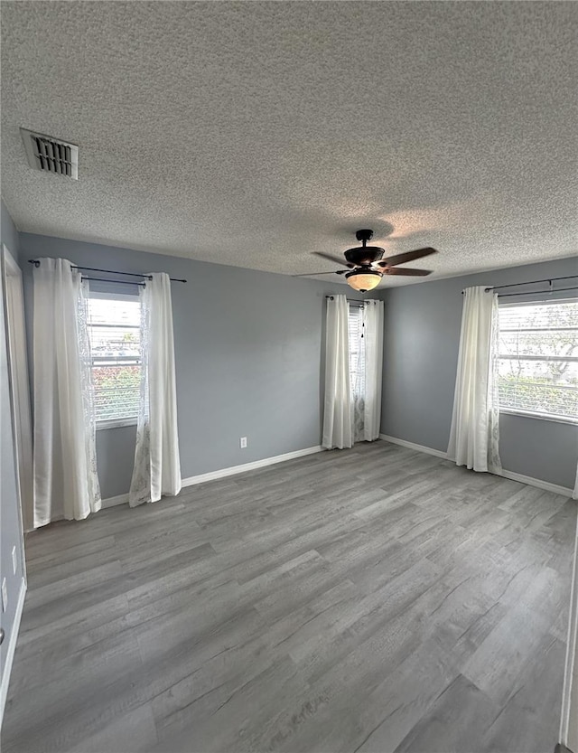 spare room featuring ceiling fan, plenty of natural light, a textured ceiling, and light wood-type flooring