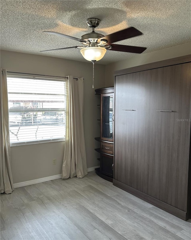 unfurnished bedroom featuring ceiling fan, a closet, light hardwood / wood-style flooring, and a textured ceiling