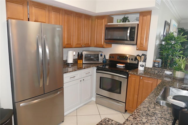 kitchen featuring dark stone countertops, sink, ornamental molding, and stainless steel appliances