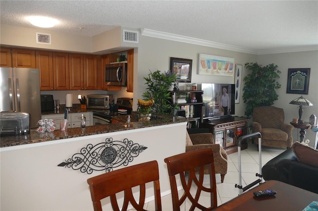 kitchen featuring light tile patterned flooring, dark stone countertops, kitchen peninsula, stainless steel appliances, and a textured ceiling