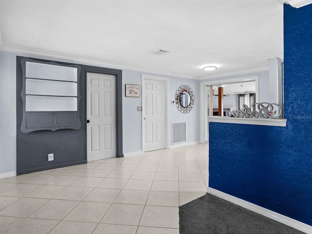 foyer entrance featuring tile patterned flooring, visible vents, and crown molding