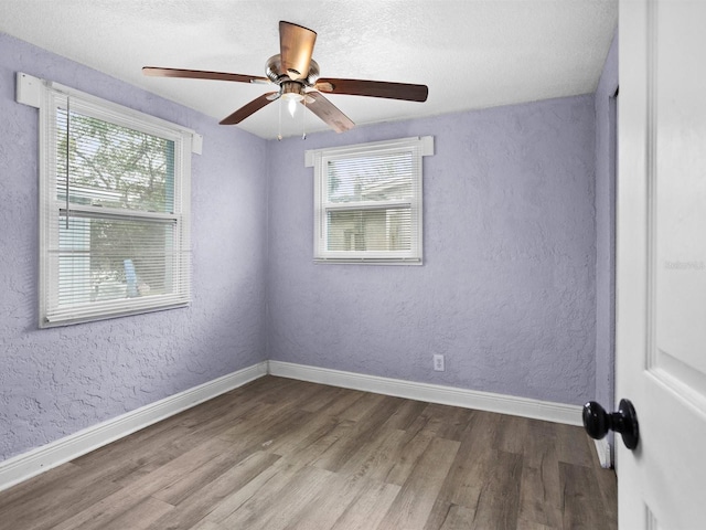 unfurnished room featuring a ceiling fan, baseboards, wood finished floors, and a textured wall