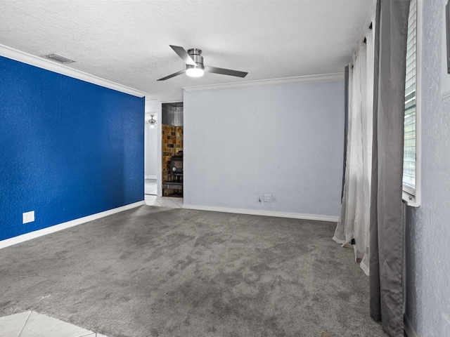 carpeted empty room with crown molding, visible vents, a textured wall, ceiling fan, and a textured ceiling