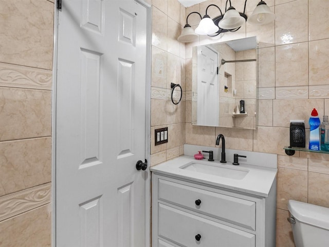bathroom with toilet, tasteful backsplash, vanity, and tile walls