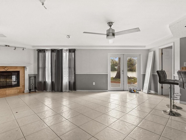 unfurnished living room with french doors, a fireplace, light tile patterned flooring, and baseboards