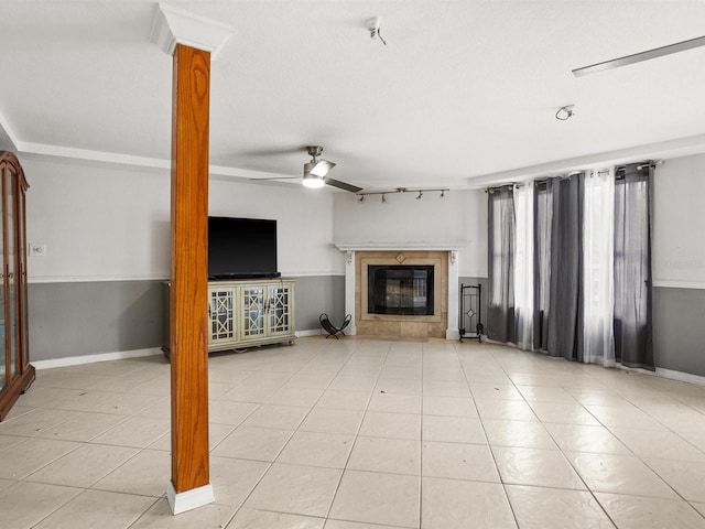 unfurnished living room featuring light tile patterned floors, baseboards, a ceiling fan, ornate columns, and a fireplace