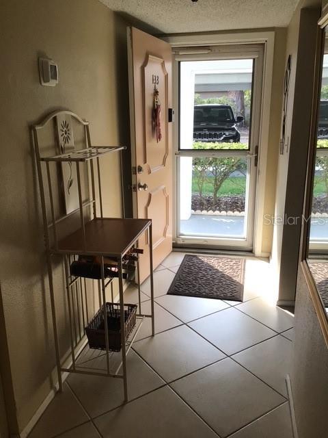 doorway to outside featuring a textured ceiling and light tile patterned floors