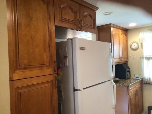 kitchen with light stone counters and white fridge