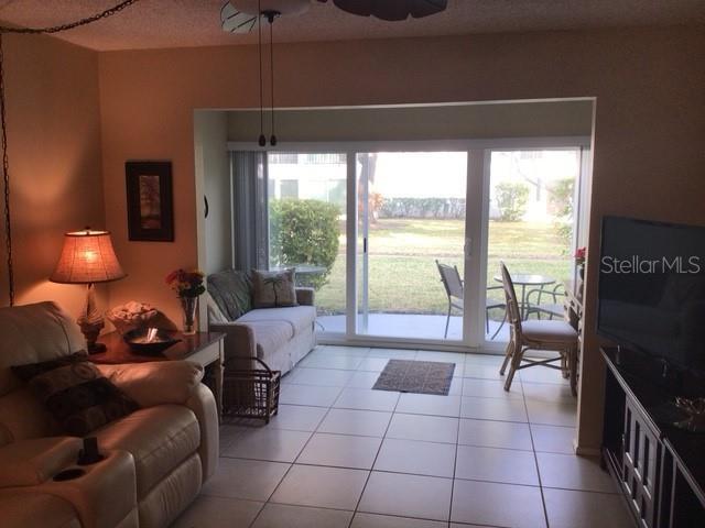 tiled living room featuring ceiling fan and a healthy amount of sunlight