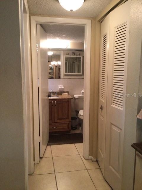 hallway with light tile patterned floors, sink, and a textured ceiling