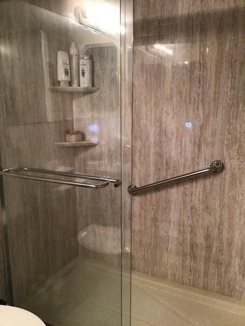 bathroom featuring a shower with shower door and toilet