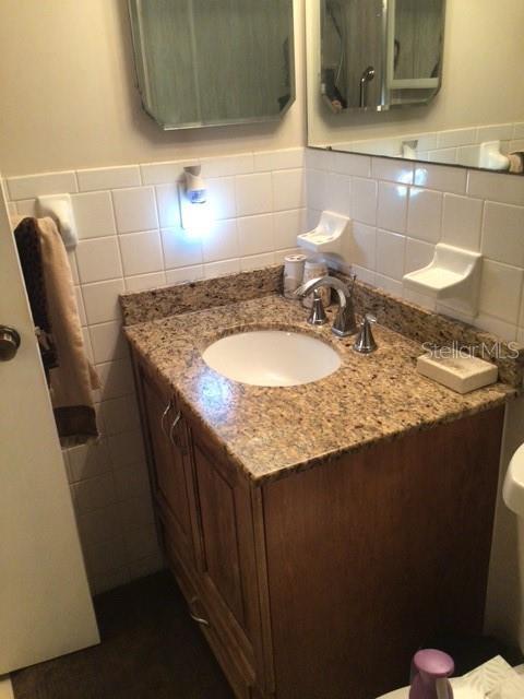 bathroom featuring vanity, tile walls, and toilet