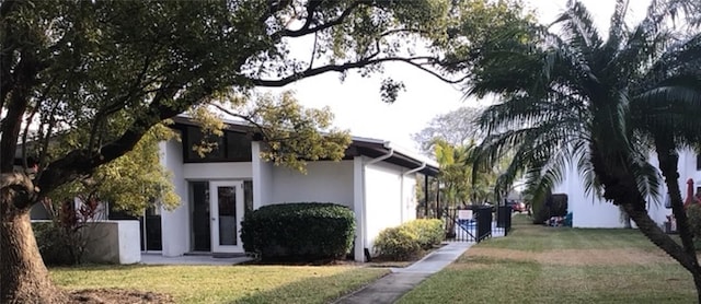 view of side of home featuring stucco siding and a lawn