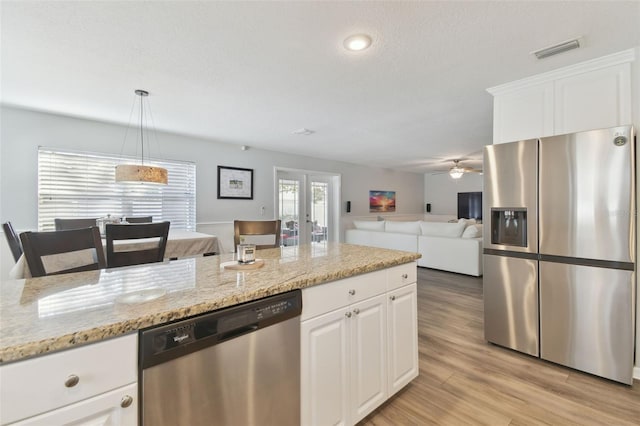 kitchen featuring french doors, appliances with stainless steel finishes, pendant lighting, light stone countertops, and white cabinets