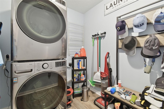 washroom featuring stacked washer / dryer and light hardwood / wood-style flooring