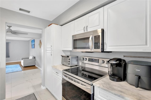 kitchen with ceiling fan, white cabinets, and appliances with stainless steel finishes