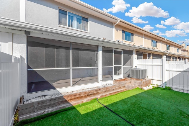 rear view of house with cooling unit, a yard, and a sunroom